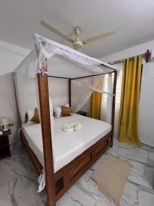 a bedroom with a canopy bed with shoes on it at Nungwi Beach Front Ex Sunrise Beach Nungwi in Nungwi