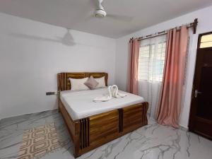 um quarto com uma cama com lençóis brancos e uma janela em Nungwi Beach Front Ex Sunrise Beach Nungwi em Nungwi