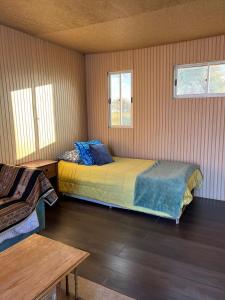 um quarto com uma cama, uma mesa e 2 janelas em Retiro Bajoestrellas em San Pedro de Atacama