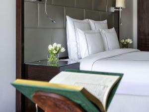 فندق سويس اوتيل مكة  في مكة المكرمة: سرير مع كتاب و مزهرية من الزهور على طاولة