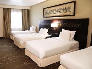 um quarto de hotel com três camas num quarto em Pullman Zamzam Madina em Al Madinah