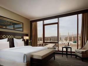 a bedroom with a large bed and a large window at Pullman Zamzam Madina in Al Madinah