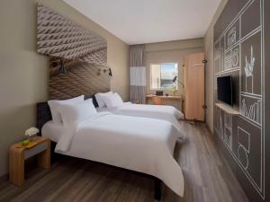 a hotel room with two beds and a television at Ibis Jeddah Malik Road in Jeddah