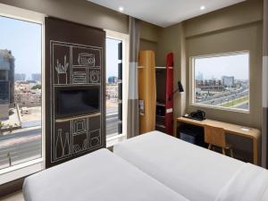 a hotel room with a bed and a tv and windows at Ibis Jeddah Malik Road in Jeddah