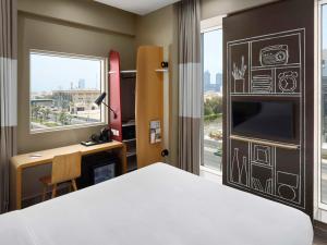 a bedroom with a bed and a desk and a window at Ibis Jeddah Malik Road in Jeddah