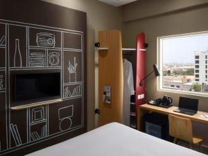 a bedroom with a bed and a desk and a window at Ibis Jeddah Malik Road in Jeddah