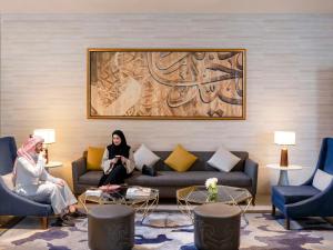 two women sitting on a couch in a living room at Movenpick Makkah Hajar Tower in Makkah