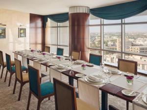 uma longa sala de jantar com uma longa mesa e cadeiras em Mövenpick Hotel Qassim em Buraydah