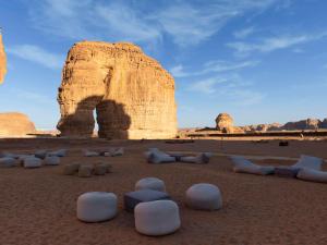 een groep stoelen in de woestijn met een rotsformatie bij Shaden Resort in Al Ula