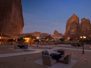a desert setting with chairs and tables in front of mountains at Shaden Resort in AlUla