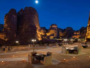 a desert area with tables and chairs in front of mountains at Shaden Resort in AlUla