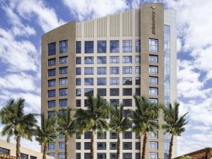 een hoog gebouw met palmbomen ervoor bij Movenpick Hotel and Residences Riyadh in Riyad
