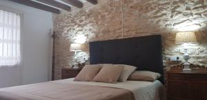 ein Schlafzimmer mit einem großen Bett und einer Steinmauer in der Unterkunft Casa de pueblo, entre mar y montaña, con spa. Plaza Mayor in Sant Jordi