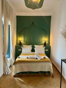 a bedroom with a large bed with a green wall at Riad Dar Marrakcha in Marrakesh