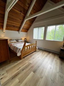 a bedroom with a bed and two windows at Chalet Mont Sainte-Anne in Beaupré +20 photos