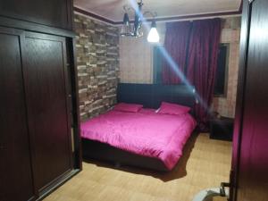 a pink bed in a room with a brick wall at الاردن in Ţāb Kirā‘