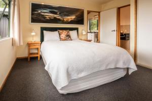 Un dormitorio con una gran cama blanca y una ventana en Goldfield Suites en Greymouth