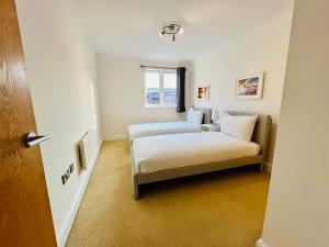 a small room with two beds and a window at Exquisite City Centre Apartment - 2 Bed 2 Bath - Free Parking - Netflix Amazon Disney Enabled Smart TV in Birmingham