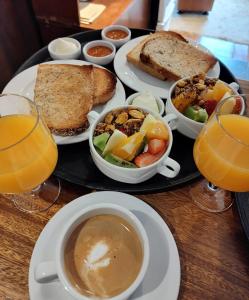 サン・マルティン・デ・ロス・アンデスにあるHotel & Spa La Cheminéeのサンドイッチとジュースを用意したテーブルの上に食べ物をトレイ
