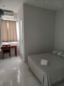 Schlafzimmer mit einem Bett, einem Schreibtisch und einem Fenster in der Unterkunft BLUES HOTEL in Guaratinguetá