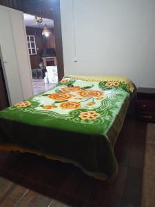 a bed with a green blanket with flowers on it at Sítio pousada e Refúgio lazer e eventos in Santana do Livramento