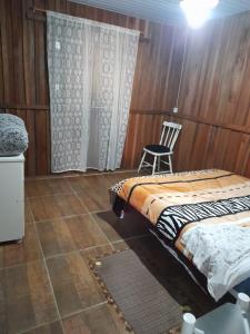 a bedroom with two beds and a chair at Sítio pousada e Refúgio lazer e eventos in Santana do Livramento