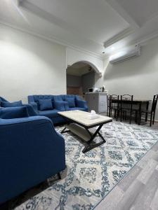 sala de estar con sofá azul y mesa en ALSEEB VIEW Serviced Hotel Suites, en Raʼs al Khafjī