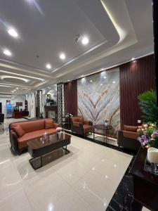 un vestíbulo con sofás, mesas y una pintura en ALSEEB VIEW Serviced Hotel Suites, en Raʼs al Khafjī