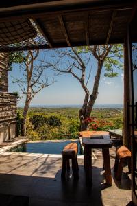 a patio with a table and a swimming pool at Divinity Villas - Uluwatu, Bali in Uluwatu