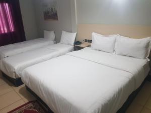 2 camas en una habitación de hotel con sábanas y almohadas blancas en Hotel INOU, en Agadir