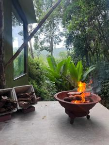 a fire pit sitting on a patio next to a window at Refugio Jabuticaba, CASA DA MATA - Você imerso na mata atlântica in Santo Antônio do Pinhal