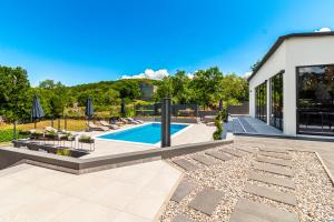 a backyard with a swimming pool and patio furniture at Jackal Holiday House with a heated pool and a jacuzzi in Lovreć