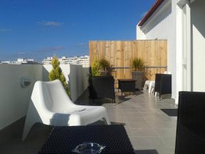 a patio with white chairs and tables on a balcony at Hotel Alnacir in Faro