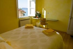 a yellow room with a bed with two towels on it at La Tata B&B in Lerici