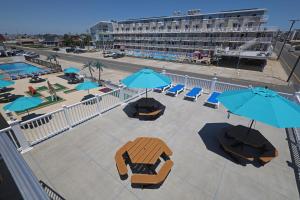 a patio with blue umbrellas and chairs and a pool at Compass Family Resort in Wildwood Crest