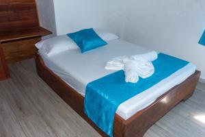 a small bed with blue and white sheets and towels at Eco Hotel La Canita in Nuquí