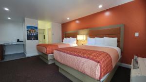 Habitación de hotel con 2 camas y paredes de color naranja en Presidio Parkway Inn en San Francisco