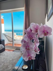 a vase with pink flowers on a table in a room at Casa Amar- Vista panorâmica in Luz +19 photos
