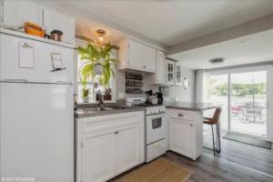 a kitchen with white cabinets and a white refrigerator at Riverfront Cottage in Fox River Grove