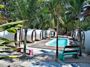 a resort pool with a chair and palm trees at Kulu Tubohostel Bacalar in Bacalar