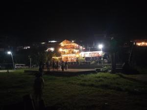 un bâtiment de nuit avec des personnes debout devant lui dans l'établissement Tran Xuan Homestay, à Ba Be18