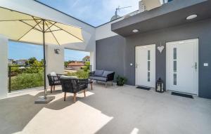 un patio con tavolo, sedie e ombrellone di Lovely Apartment In Sukosan With Wifi a Sukošan (San Cassiano) Altre 40 foto