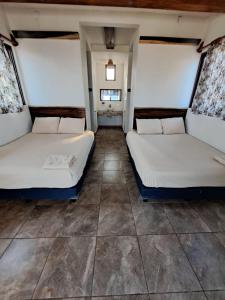 two beds sitting in a room with tile floors at Cabañas Alta Mar in Guayabas