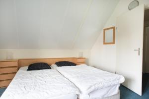 a bedroom with a white bed with two pillows on it at Hello Zeeland - Vakantiehuis Stern 228 in Breskens