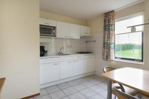 a kitchen with white cabinets and a table and a window at Hello Zeeland - Vakantiehuis Stern 228 in Breskens