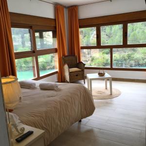 een slaapkamer met een bed, een stoel en ramen bij Hostal Avenjúcar in Tolosa