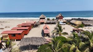 eine Gruppe von Hütten an einem Strand mit dem Meer in der Unterkunft Cabañas Alta Mar in Guayabas