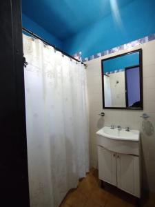 a bathroom with a white shower curtain and a sink at Como en casa - hospedaje del valle in San Fernando del Valle de Catamarca