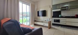 a living room with a couch and a tv and a kitchen at Apartamento próximo praia in Florianópolis