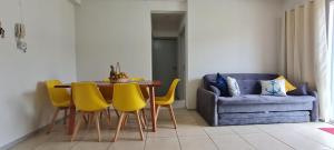 a living room with a table and yellow chairs at Apartamento próximo praia in Florianópolis +9 photos